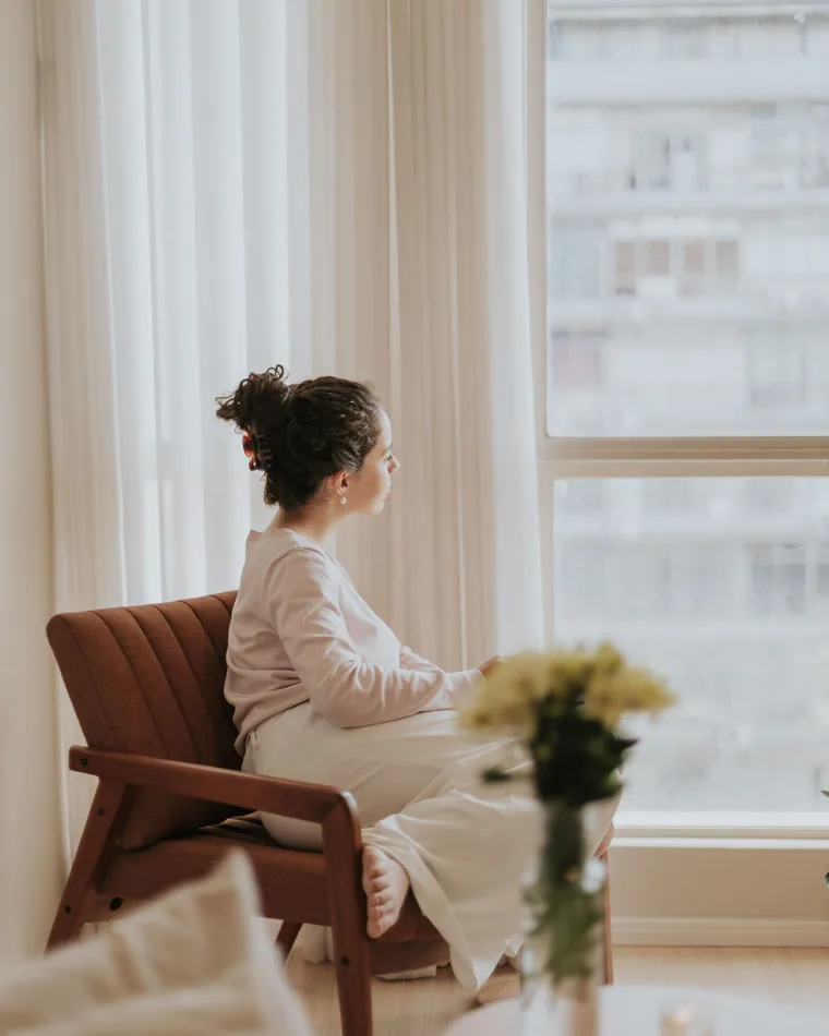 A woman resting in a chair beside a bright window